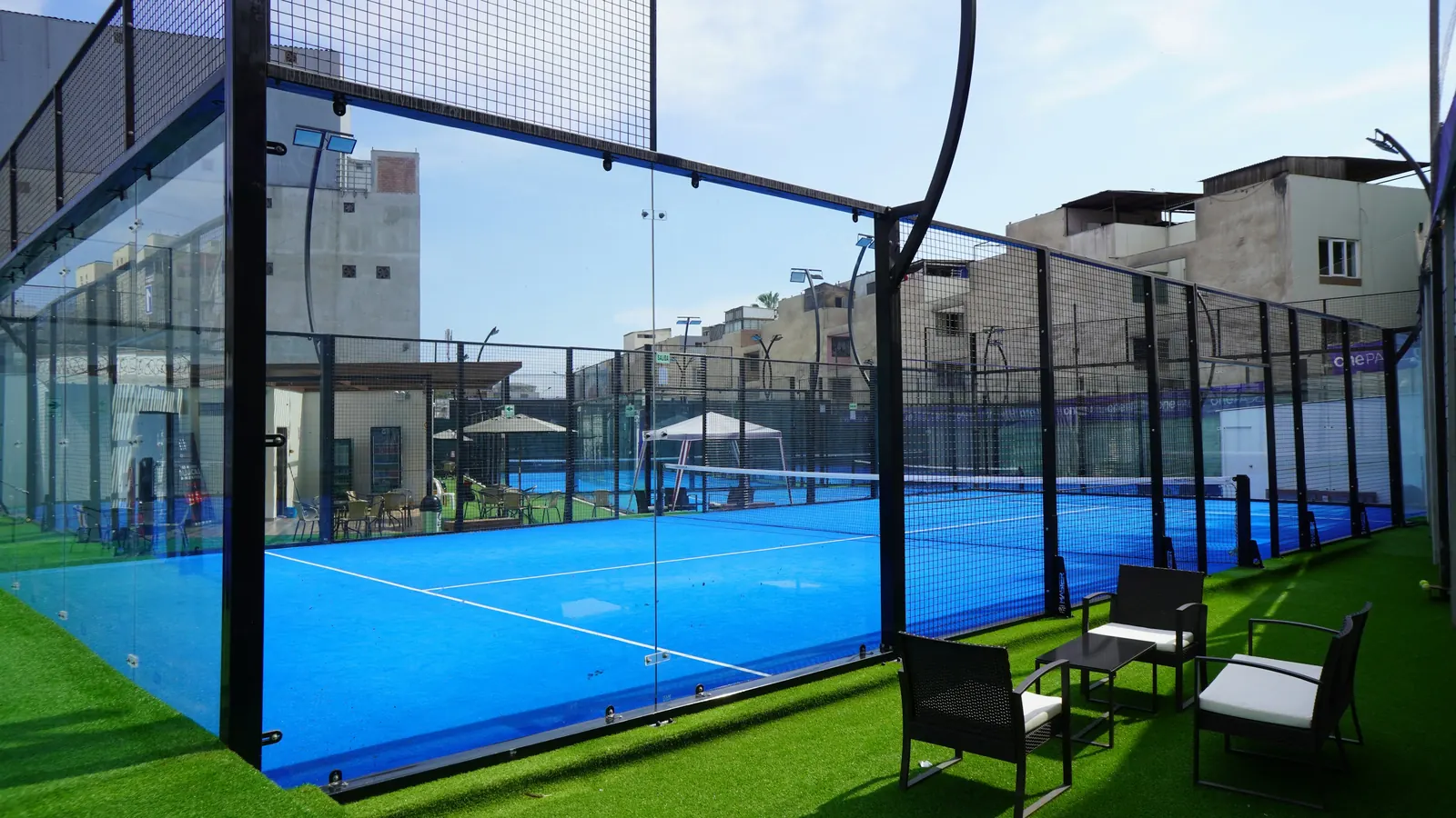 An outdoor padel court with seating on artificial grass