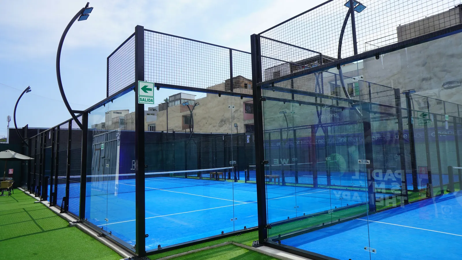A row of glass-walled outdoor padel courts