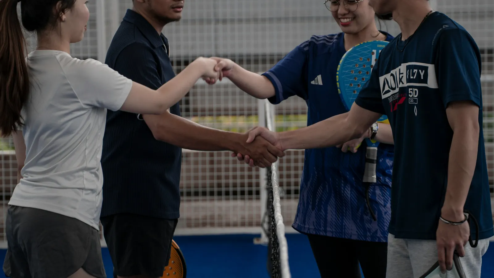 Four players shaking hands at the net after a match