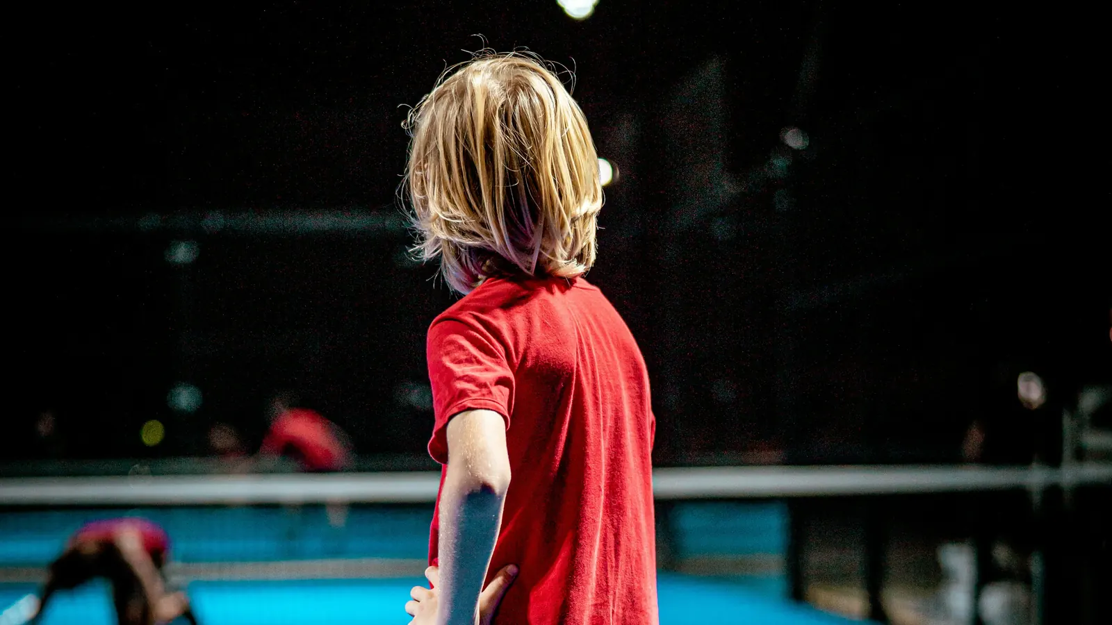 A young player waiting on an indoor court