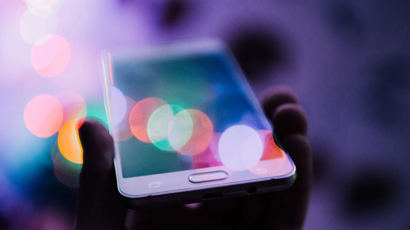 A smartphone held up against coloured lights