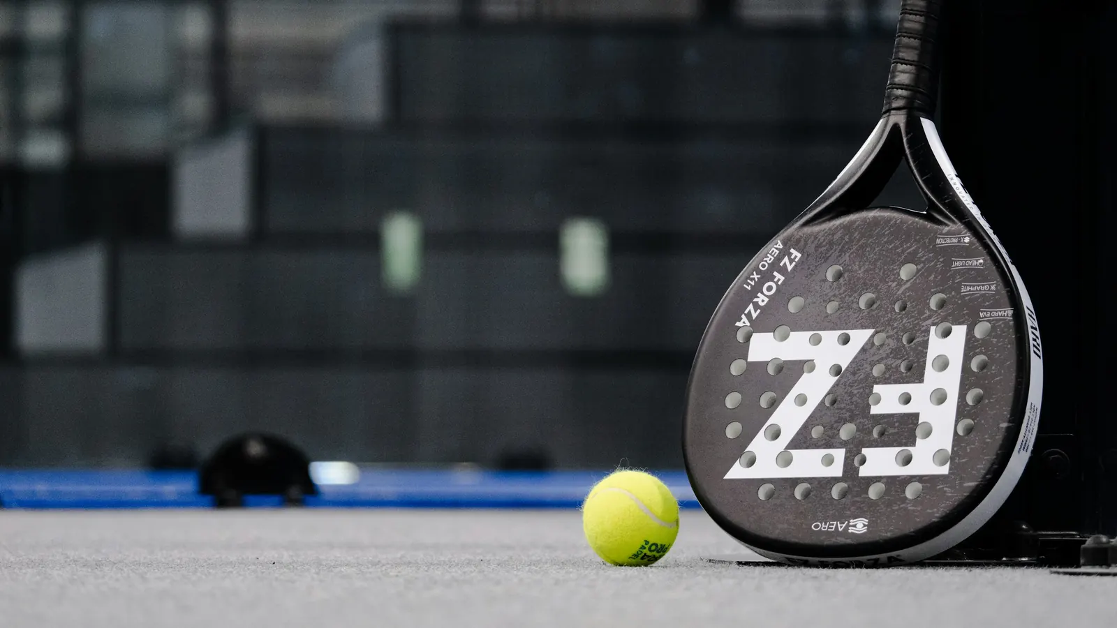 A padel racket and ball resting on an indoor court