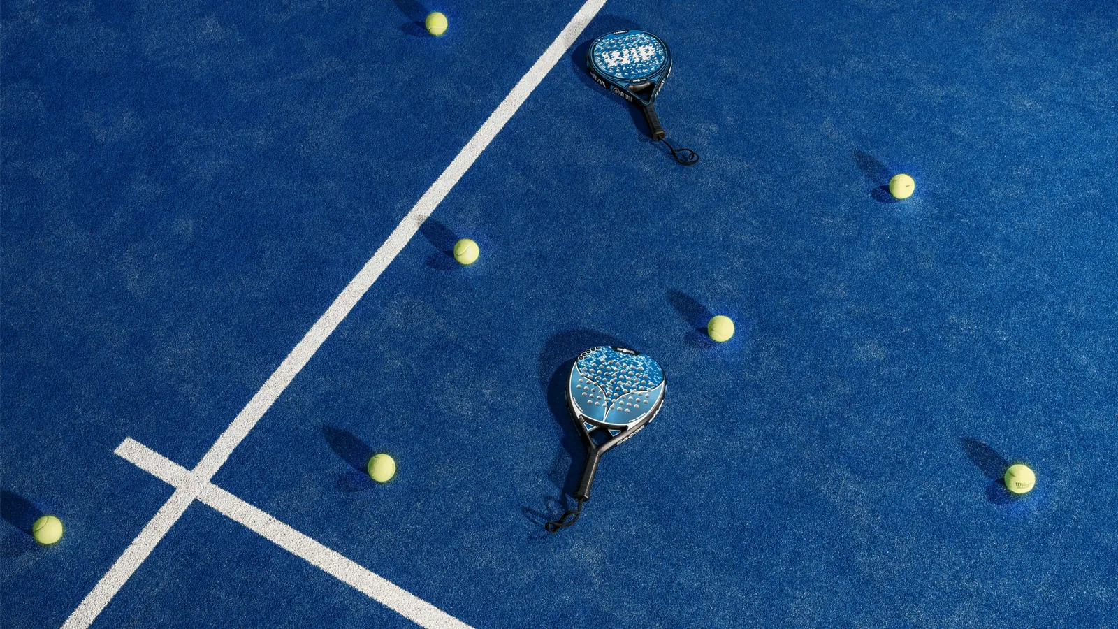 Two rackets and balls on a blue court